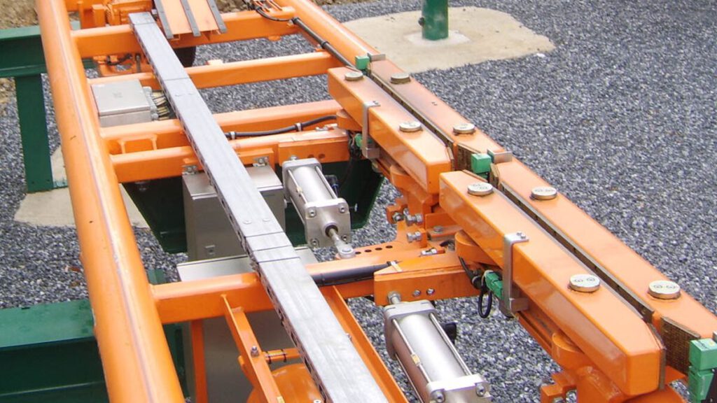 Nahaufnahme einer Friction Brake (Reibungsbremse) mit orangefarbenen Bremsbacken und Metallführungen, die für das Abbremsen von Achterbahnzügen sorgt.