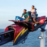 Zwei Personen fahren auf der Bolt-Achterbahn an Bord eines Kreuzfahrtschiffs mit Blick auf das offene Meer unter klarem Himmel.