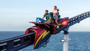 Zwei Personen fahren auf der Bolt-Achterbahn an Bord eines Kreuzfahrtschiffs mit Blick auf das offene Meer unter klarem Himmel.